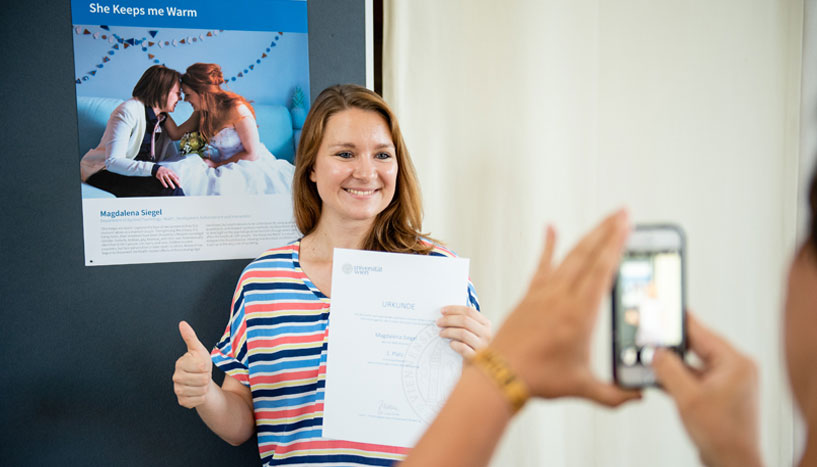 Magdalena Siegel mit Urkunde in der Hand vor ihrem Siegerbild