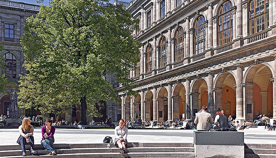 Studierende sitzen im Arkadenhof der Universität Wien in der Sonne